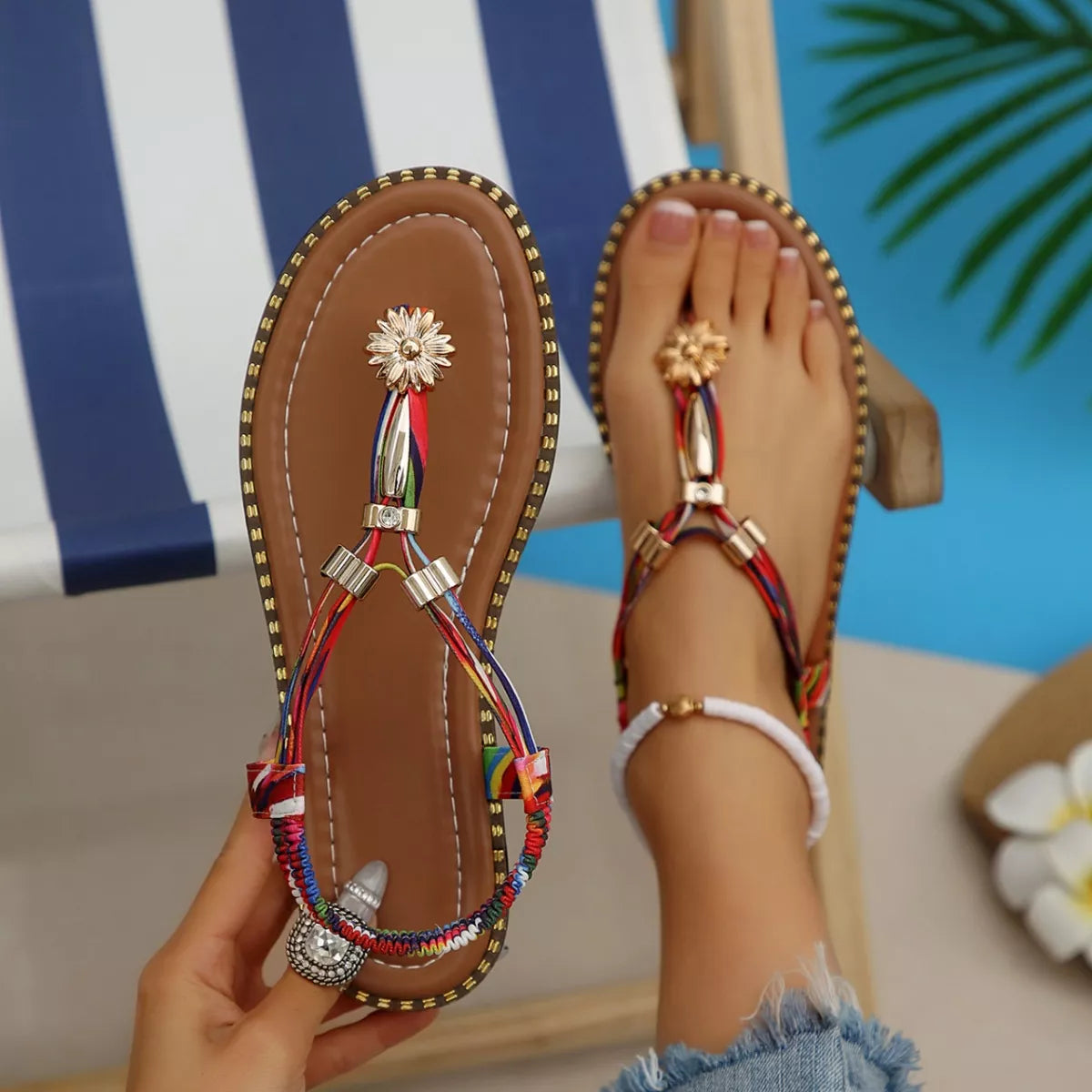 Colorful sandals with decorative straps worn by a person sitting by a pool.