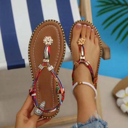 Colorful sandals with decorative straps worn by a person sitting by a pool.