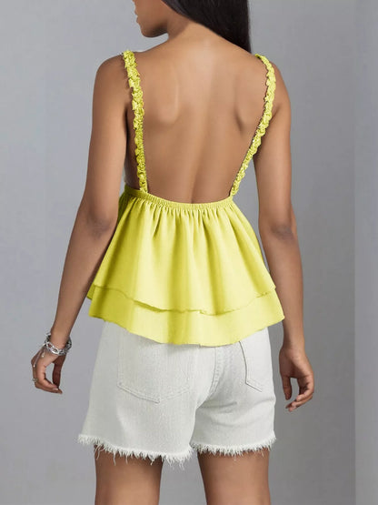 Yellow top with thin straps and white shorts on a gray background