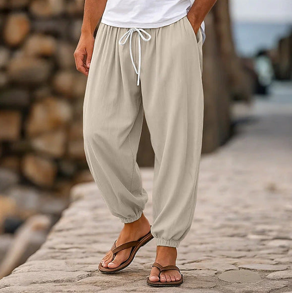 Person wearing beige drawstring pants standing on a stone path with wooden logs in the background.