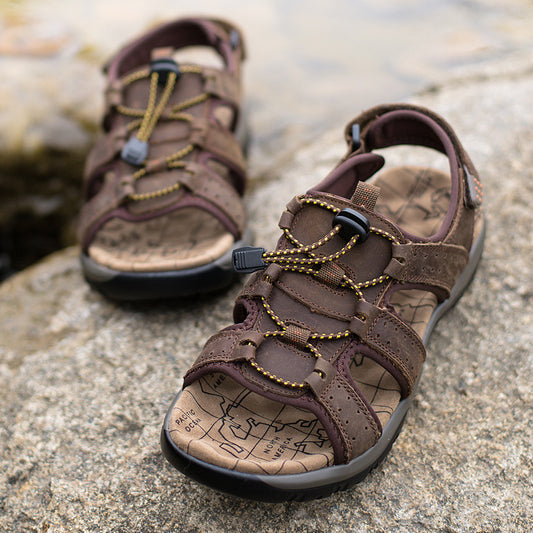 Brown sandals with braided straps on a stone surface
