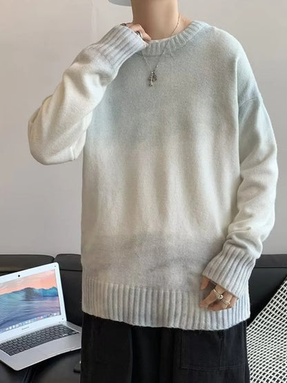 Person wearing a light gray sweater with a laptop on a desk in the background