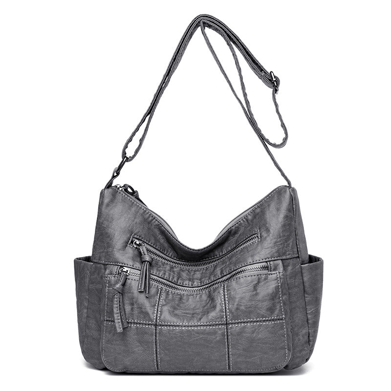 Gray shoulder bag with multiple zippers on a white background