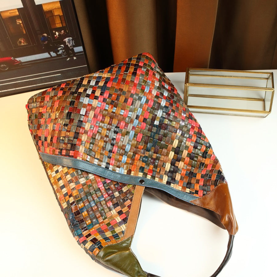 Multicolored woven handbag on a white surface with a blurred background