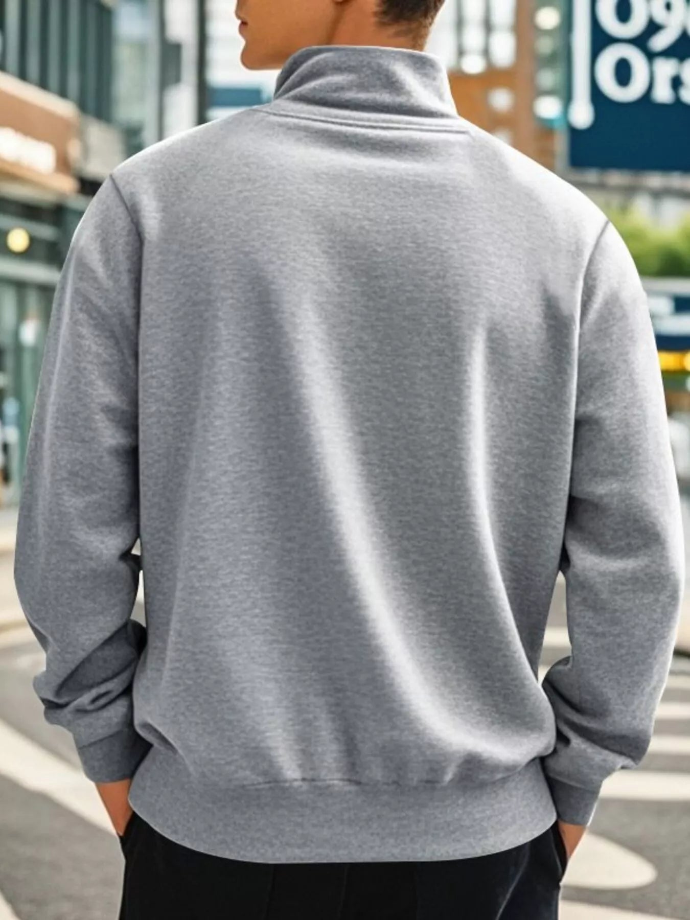 Person wearing a gray sweatshirt with a blurred urban background