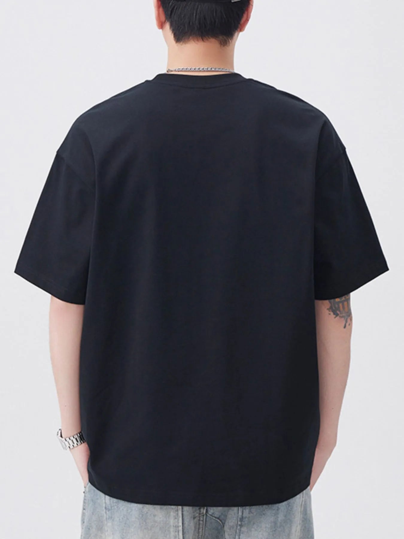 Person wearing a black t-shirt on a plain background