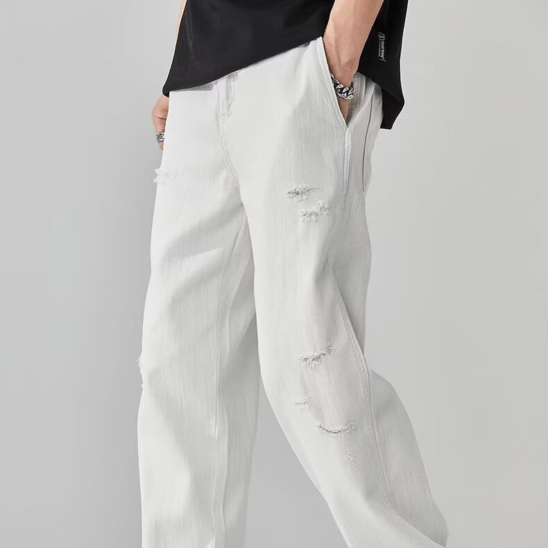 White distressed jeans worn by a person on a gray background