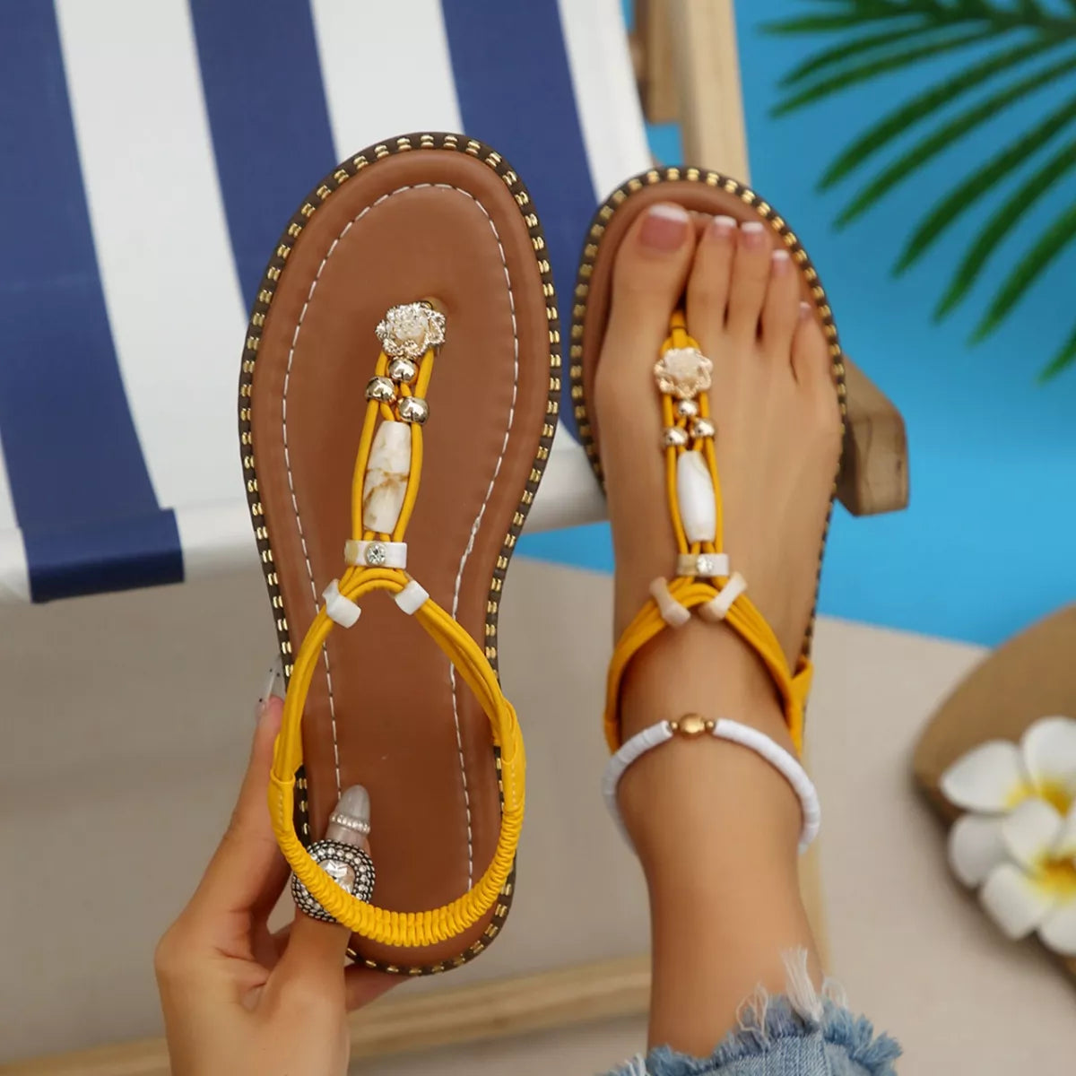 Yellow sandals with decorative straps worn by a person sitting by a pool