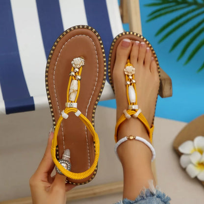 Yellow sandals with decorative straps worn by a person sitting by a pool