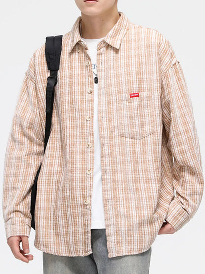 Person wearing a plaid shirt with a visible brand logo on a white background