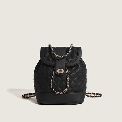 Black quilted handbag with gold chain detail on a light beige background