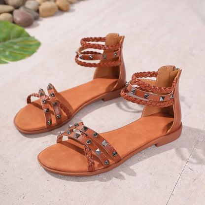 Pair of brown sandals with braided straps on a light surface.