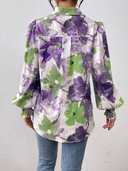 Person wearing a floral-patterned shirt with purple and green flowers on a plain background