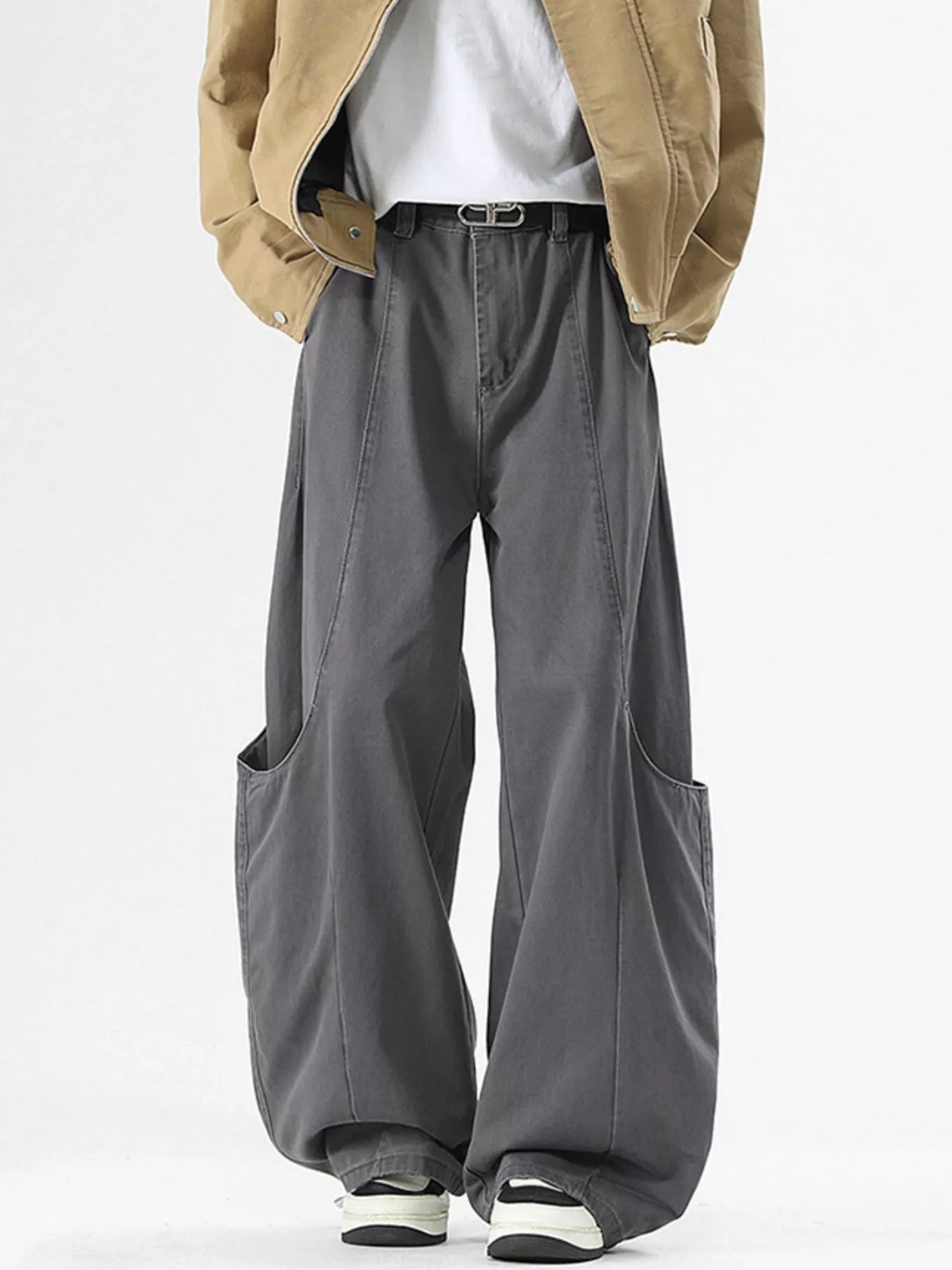 Person wearing a beige jacket, white shirt, and gray wide-leg pants on a white background