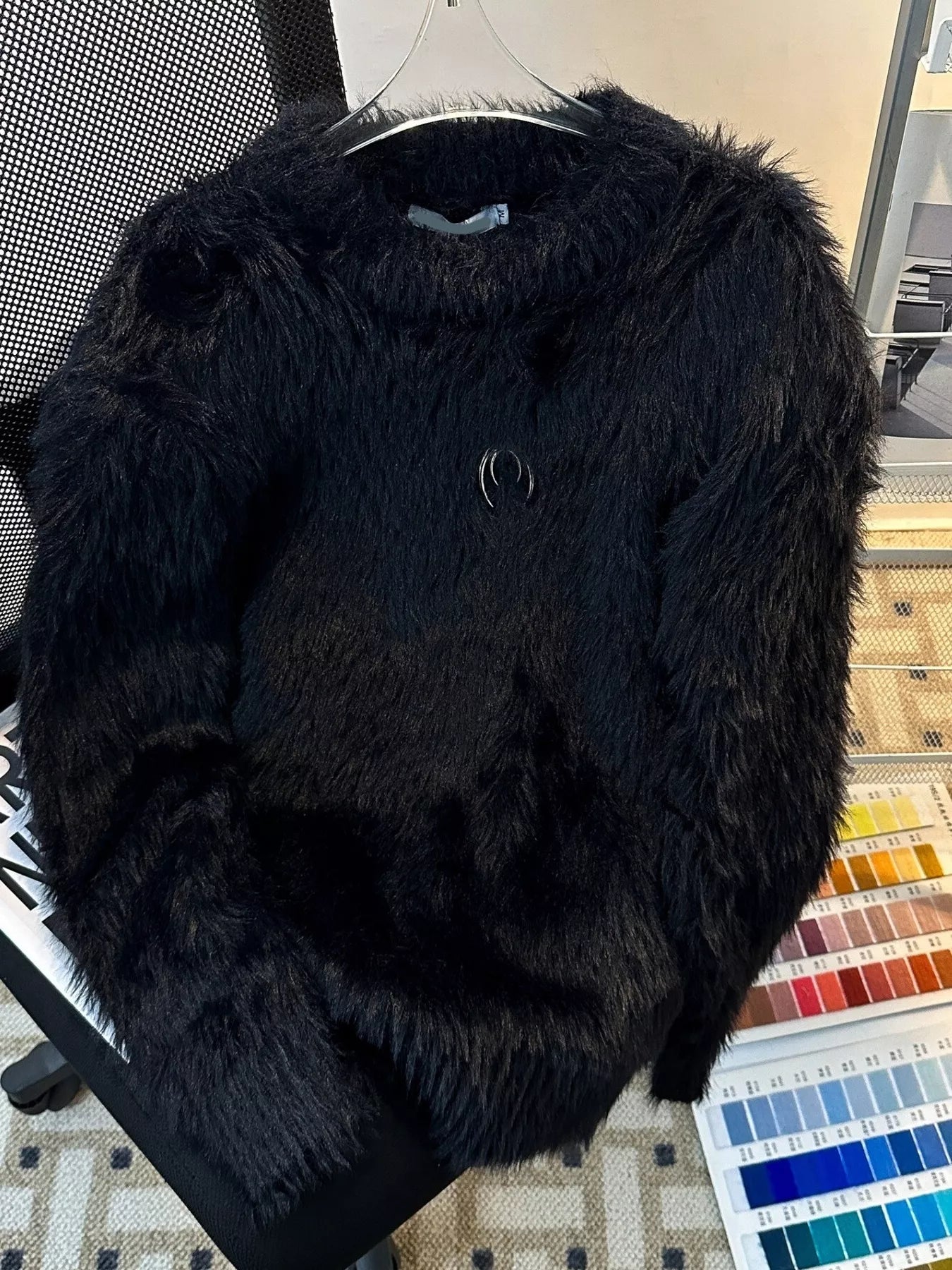 Black fluffy sweater on a hanger with a color swatch below