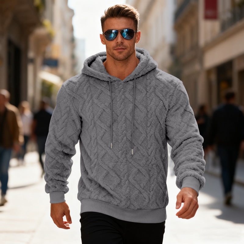 Man wearing a gray cable knit hoodie and sunglasses on a city street.