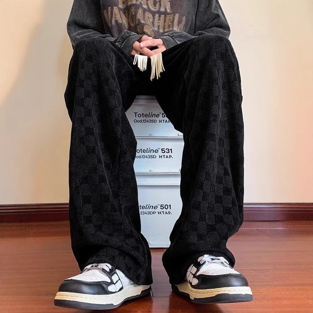 Person wearing black checkered pants and black and white sneakers sitting on a stack of boxes.