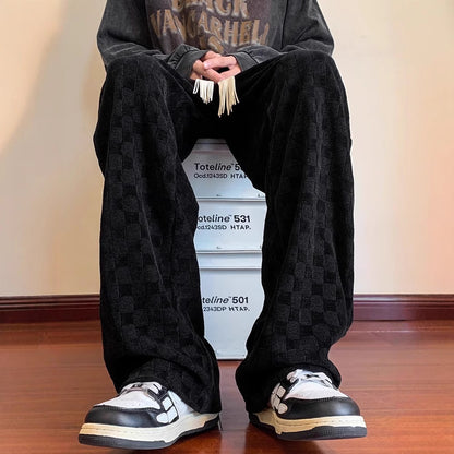 Person wearing black checkered pants and black and white sneakers sitting on a stack of boxes.