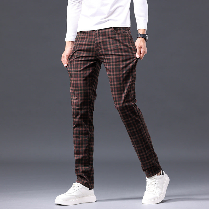 Person wearing brown plaid pants and white sneakers on a gray background
