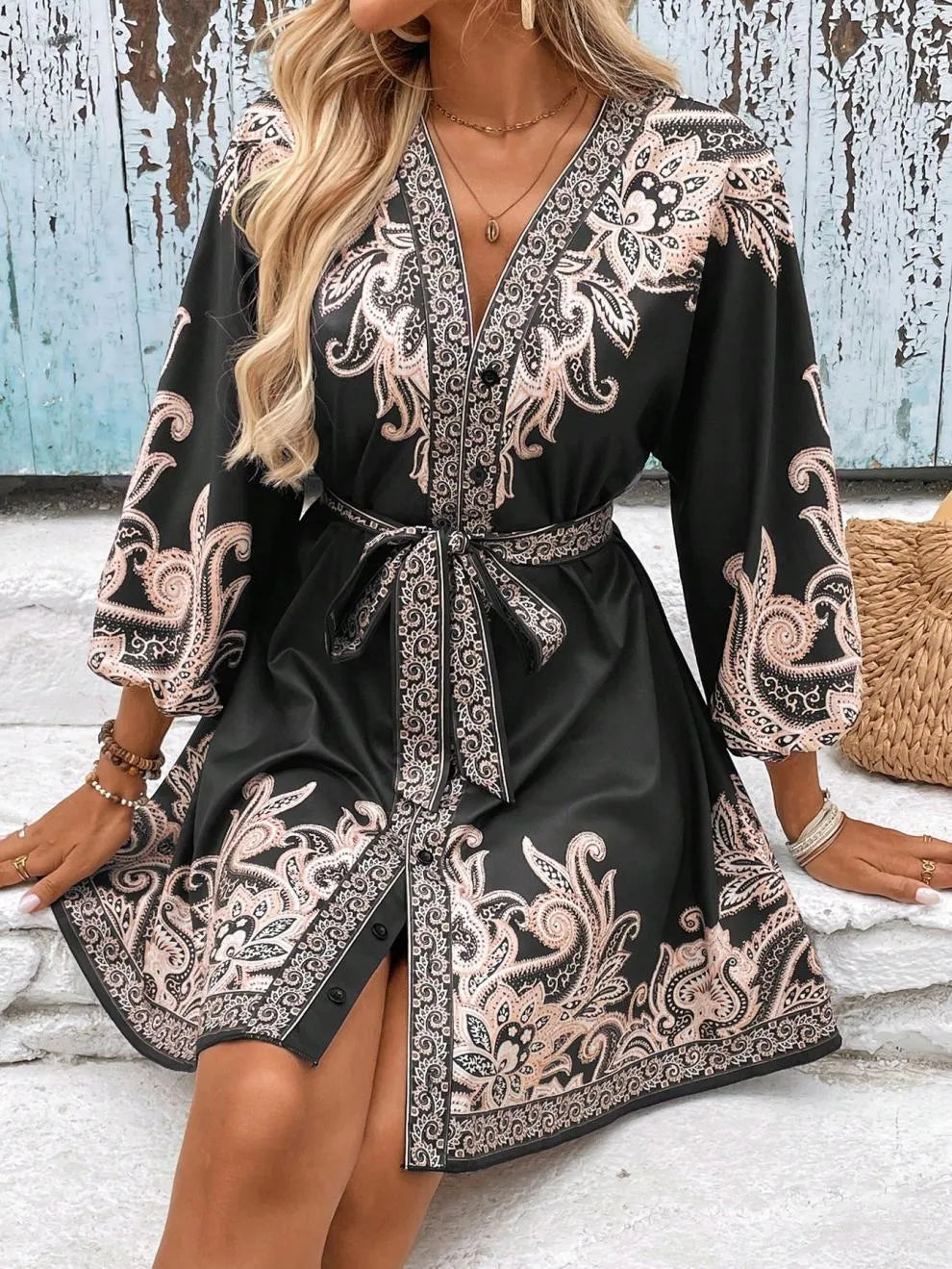 Woman wearing a black dress with intricate white patterns on a wooden floor.