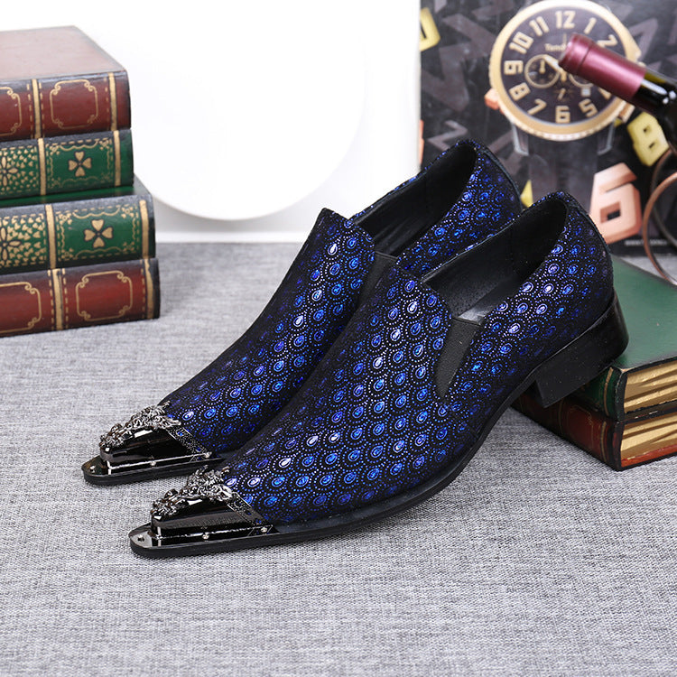 Blue patterned dress shoes with decorative toes on a textured surface.