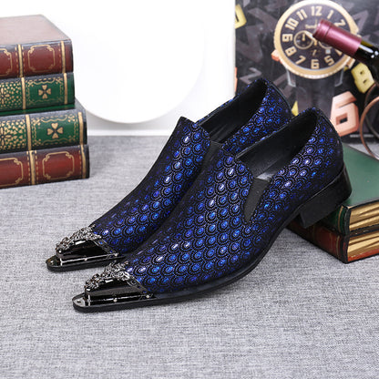 Blue patterned dress shoes with decorative toes on a textured surface.