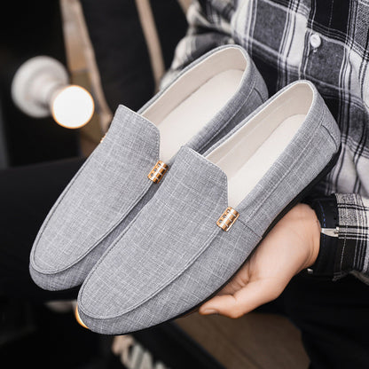 Gray loafers held by a person wearing a plaid shirt.