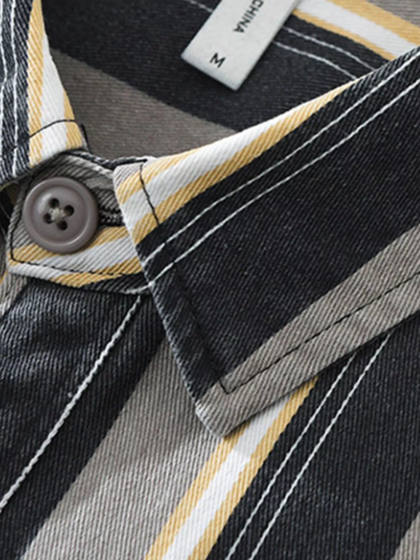 Close-up of a button on a striped shirt with a brand label.