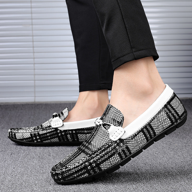 Black pattern loafers worn with black pants on a neutral background