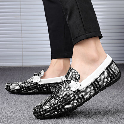 Black pattern loafers worn with black pants on a neutral background
