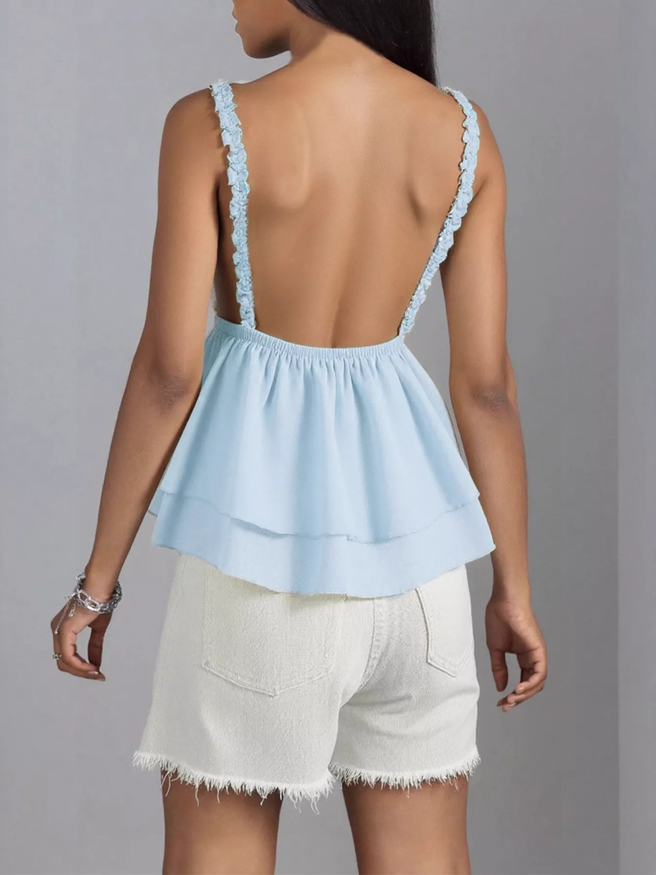 Light blue top with thin straps and white shorts on a gray background
