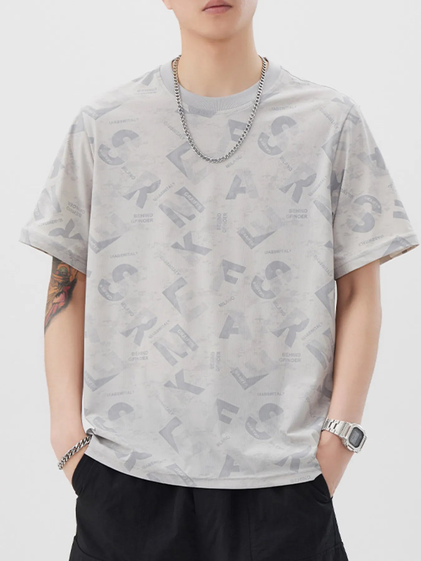 Person wearing a gray t-shirt with letter pattern and black pants on a white background