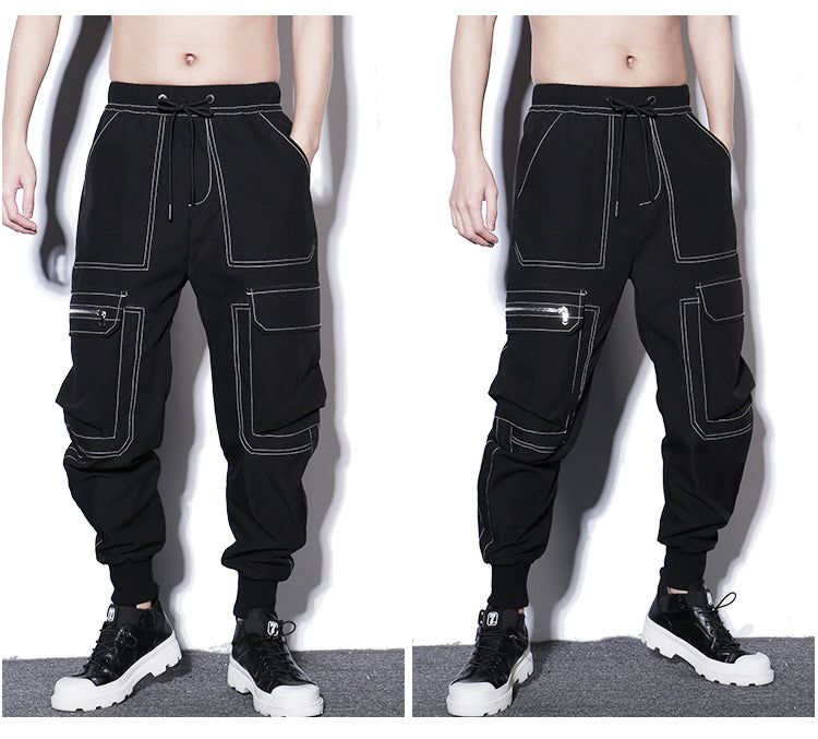 Black cargo pants with white stitching worn by a person on a gray background