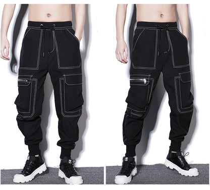 Black cargo pants with white stitching worn by a person on a gray background